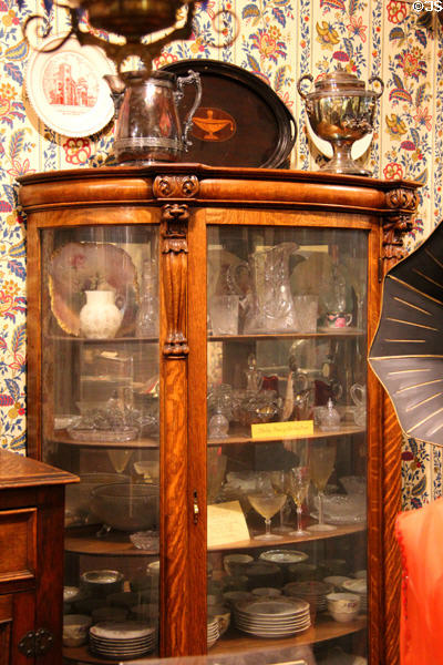 Vitrine with carved wood framing displaying fine glassware & china at El Dorado County Historical Museum. Placerville, CA.