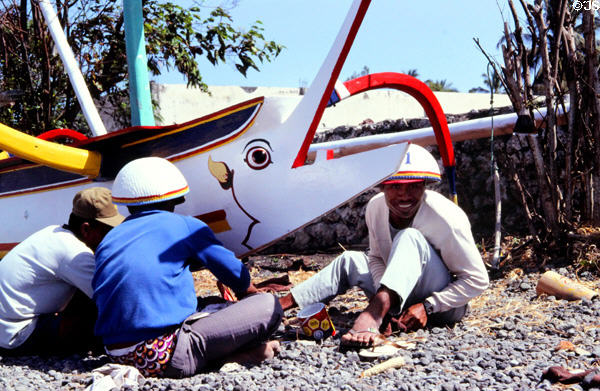 Boatmen work on boat painted with eye to ward off evil. Bali, Indonesia.
